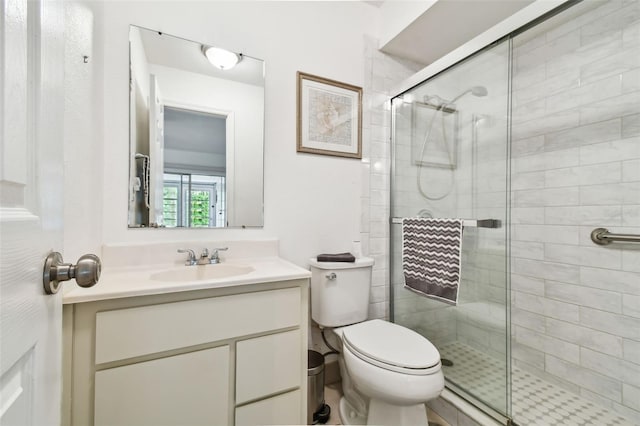 bathroom with toilet, vanity, and a shower with door