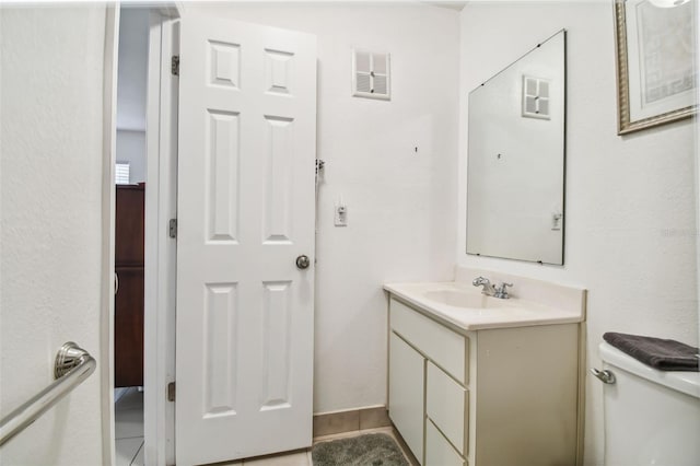 bathroom with tile patterned flooring, vanity, and toilet