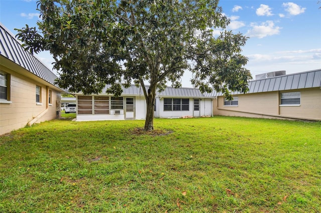 back of property featuring a sunroom and a lawn