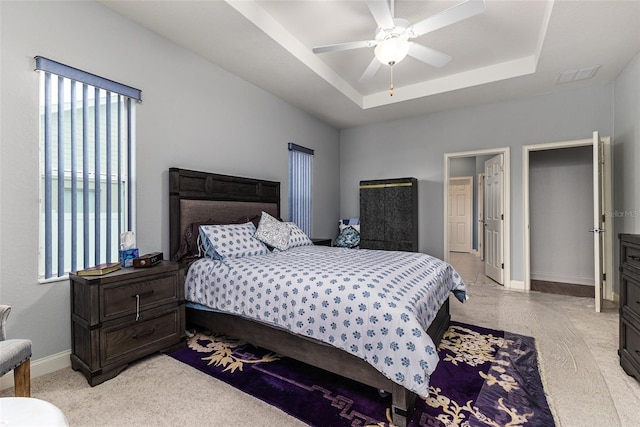 carpeted bedroom featuring ceiling fan and a tray ceiling