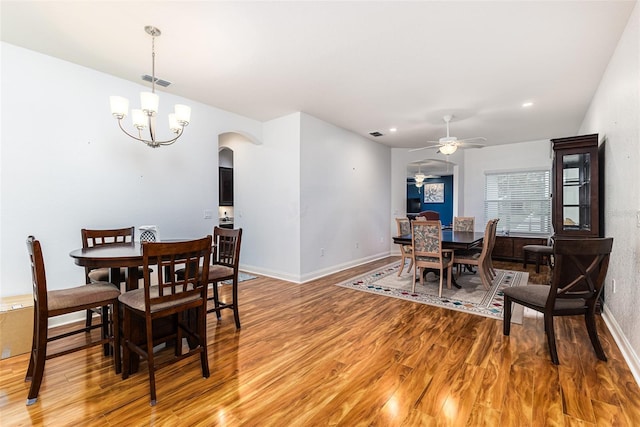 dining room with ceiling fan with notable chandelier and hardwood / wood-style flooring