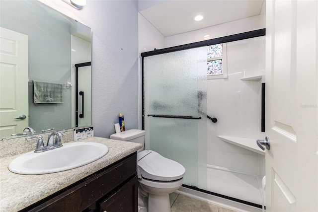 bathroom with vanity, a shower with door, tile patterned flooring, and toilet