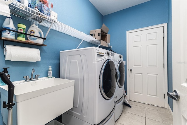 clothes washing area with washer and dryer, light tile patterned floors, and sink