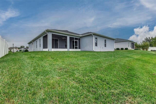 rear view of property featuring a sunroom and a lawn