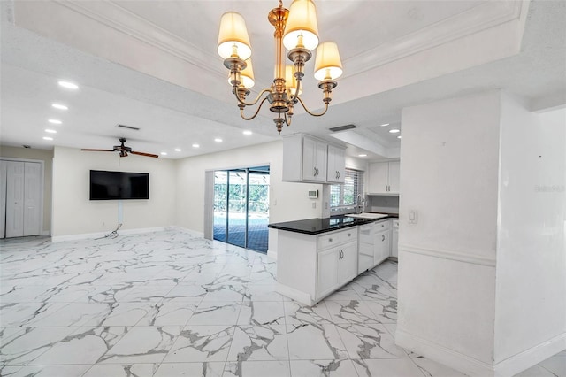 kitchen with white cabinets, ceiling fan with notable chandelier, a raised ceiling, and decorative light fixtures