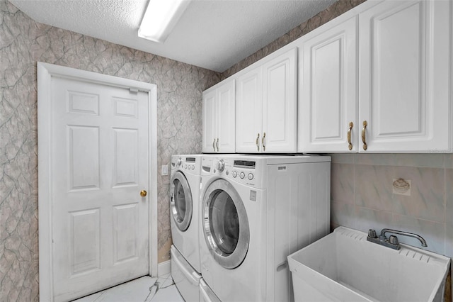 laundry room featuring cabinets, a textured ceiling, sink, and independent washer and dryer