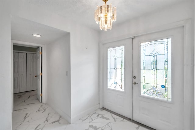 entryway with french doors, a notable chandelier, and a textured ceiling