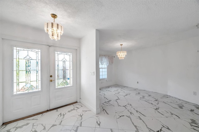 foyer entrance with a chandelier, a wealth of natural light, and a textured ceiling