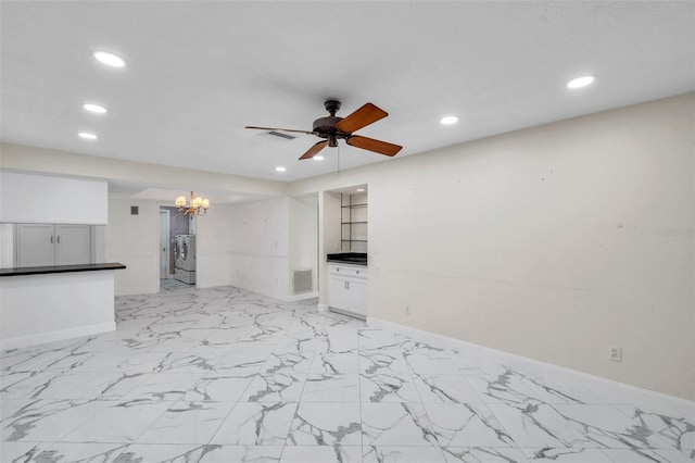 unfurnished living room featuring ceiling fan with notable chandelier