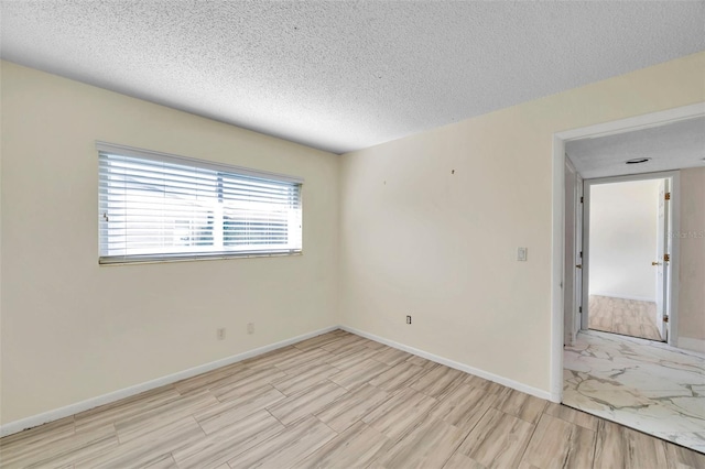 unfurnished room with a textured ceiling and light hardwood / wood-style floors