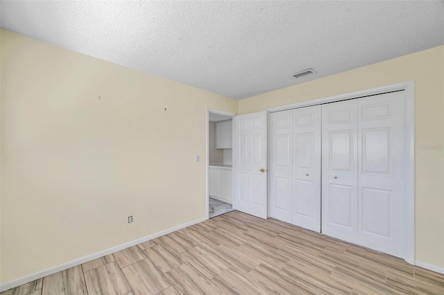 unfurnished bedroom with a textured ceiling, a closet, and light hardwood / wood-style flooring