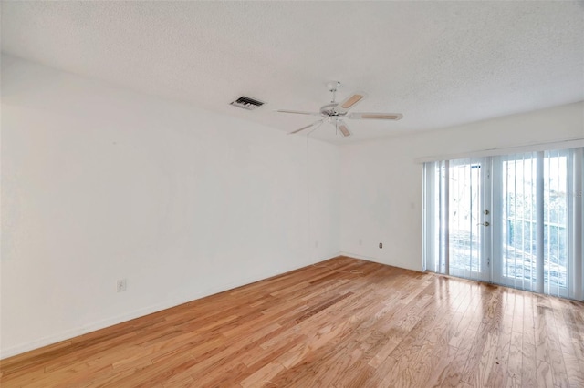 spare room with french doors, light hardwood / wood-style flooring, a textured ceiling, and ceiling fan