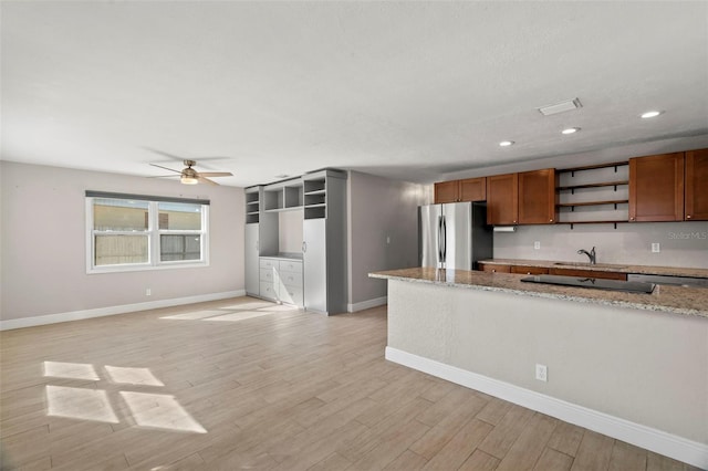 kitchen featuring light stone counters, sink, light wood-type flooring, and appliances with stainless steel finishes