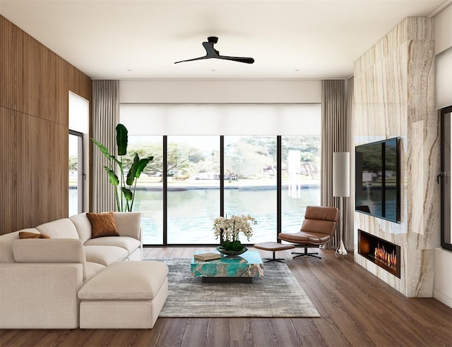 living room with a large fireplace, ceiling fan, and dark wood-type flooring