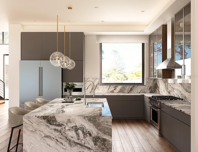 kitchen featuring light stone counters, decorative backsplash, a breakfast bar, appliances with stainless steel finishes, and light wood-type flooring