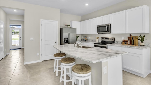 kitchen with white cabinetry, stainless steel appliances, sink, and an island with sink