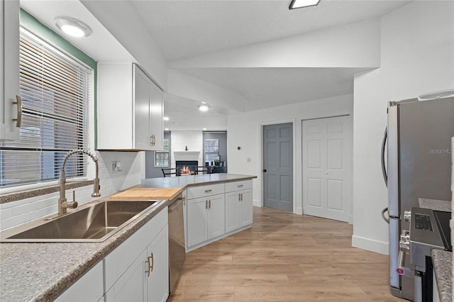 kitchen with lofted ceiling, sink, light hardwood / wood-style flooring, appliances with stainless steel finishes, and white cabinetry