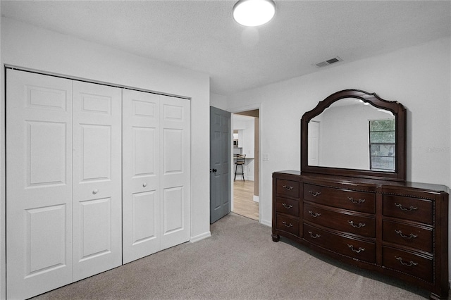 carpeted bedroom featuring a textured ceiling and a closet