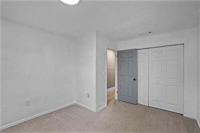 unfurnished bedroom featuring carpet flooring, a textured ceiling, and a closet