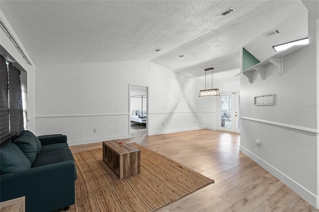 living room with light hardwood / wood-style floors, a textured ceiling, and vaulted ceiling