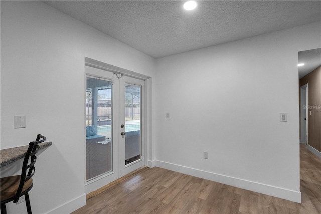 interior space featuring french doors, light hardwood / wood-style floors, and a textured ceiling