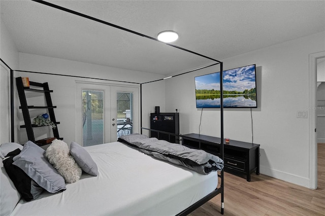 bedroom with hardwood / wood-style floors, access to exterior, a textured ceiling, and french doors