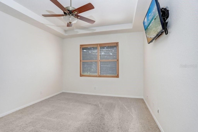 unfurnished room featuring a tray ceiling, carpet, and ceiling fan