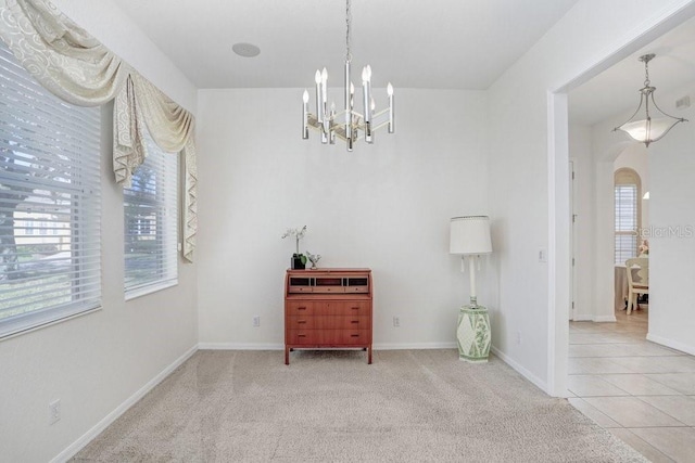 carpeted empty room featuring a chandelier