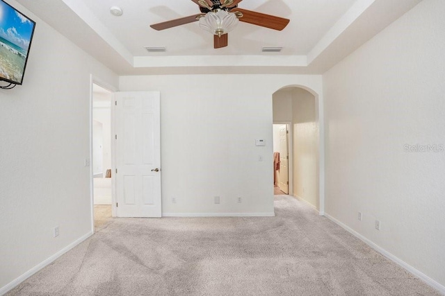 carpeted spare room featuring ceiling fan and a raised ceiling