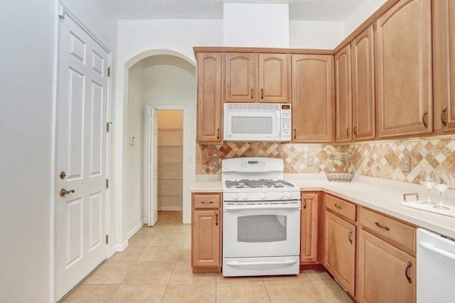 kitchen featuring light brown cabinets, tasteful backsplash, light tile patterned floors, and white appliances