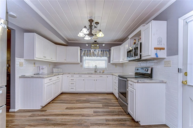 kitchen featuring stainless steel appliances, white cabinets, ornamental molding, light wood-type flooring, and decorative light fixtures