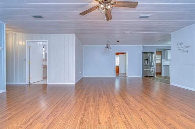 unfurnished living room with wood walls, hardwood / wood-style floors, and crown molding