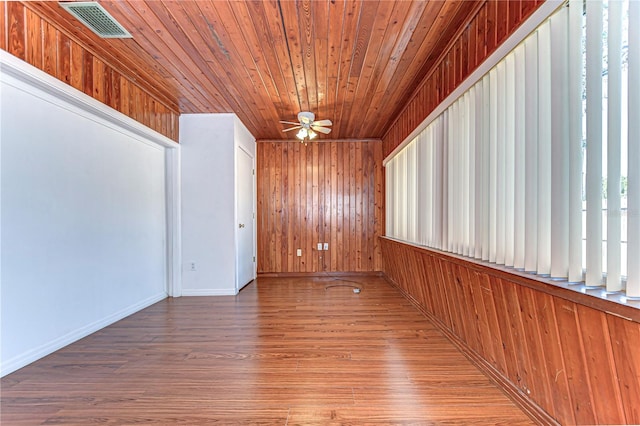 unfurnished room featuring wood walls, wood-type flooring, and ceiling fan