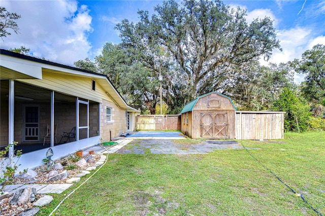 view of yard with a patio, a sunroom, and a shed