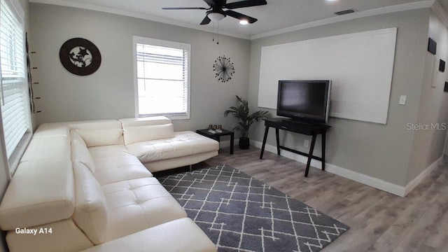 living room featuring a healthy amount of sunlight, ceiling fan, ornamental molding, and hardwood / wood-style flooring