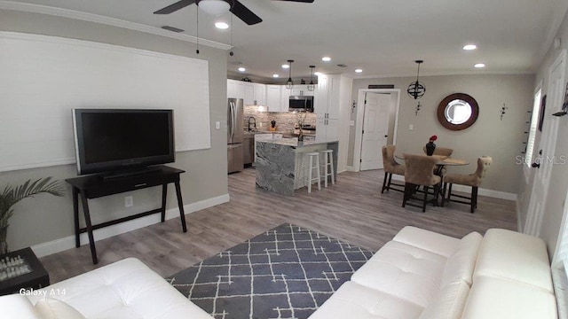 living room with ceiling fan, ornamental molding, and wood-type flooring