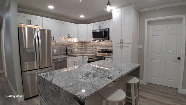 kitchen with light stone counters, white cabinets, appliances with stainless steel finishes, and sink