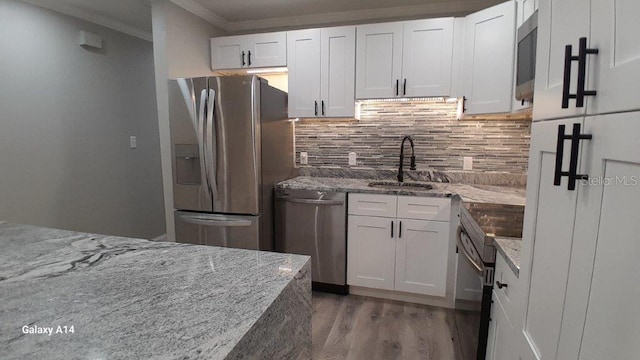 kitchen with stainless steel appliances, white cabinetry, sink, and light stone counters