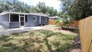 rear view of property with a yard, a sunroom, and a patio area