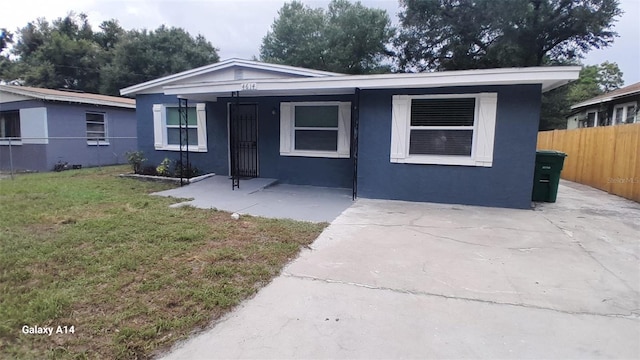 view of front of home featuring stucco siding, a front lawn, and fence