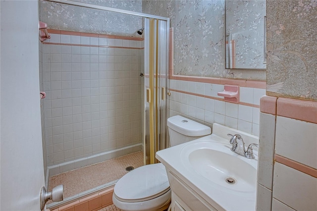 bathroom with tile walls, walk in shower, vanity, and toilet