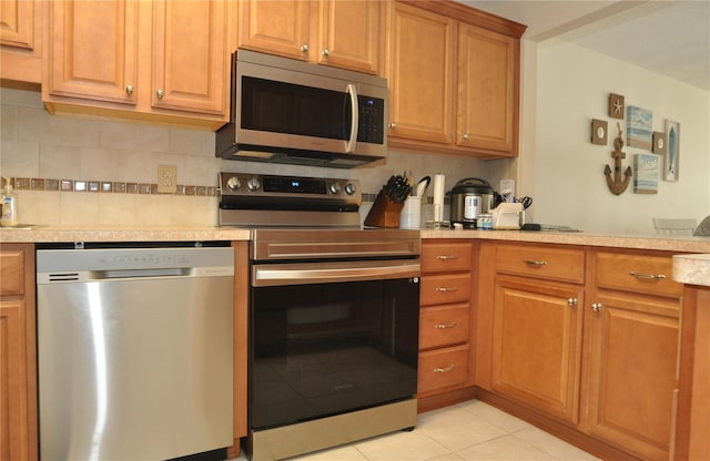 kitchen featuring light tile patterned flooring, decorative backsplash, and appliances with stainless steel finishes