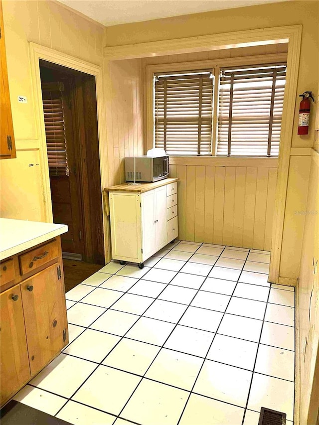 kitchen with plenty of natural light, wooden walls, and light tile patterned floors