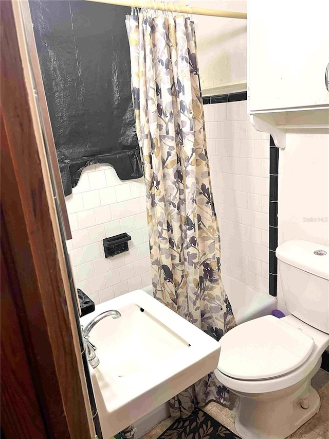 full bathroom with toilet, tile walls, tile patterned flooring, sink, and shower / bathtub combination with curtain