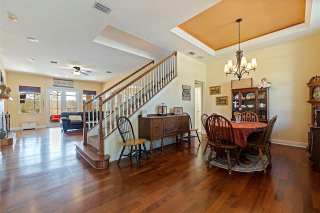 dining area featuring ceiling fan with notable chandelier, dark hardwood / wood-style floors, and a tray ceiling