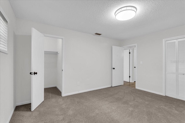 unfurnished bedroom with a textured ceiling and carpet floors