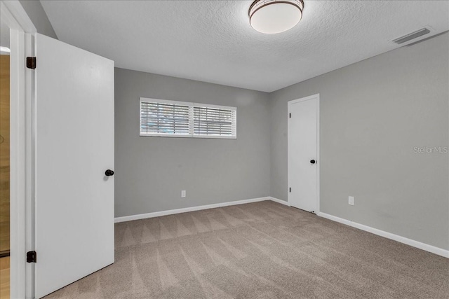 empty room featuring a textured ceiling and light carpet