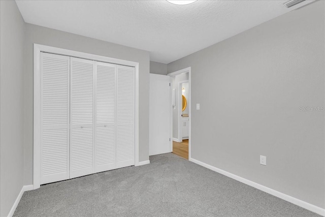 unfurnished bedroom with a closet, a textured ceiling, and light colored carpet