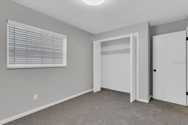 unfurnished bedroom with dark colored carpet, a closet, and a textured ceiling