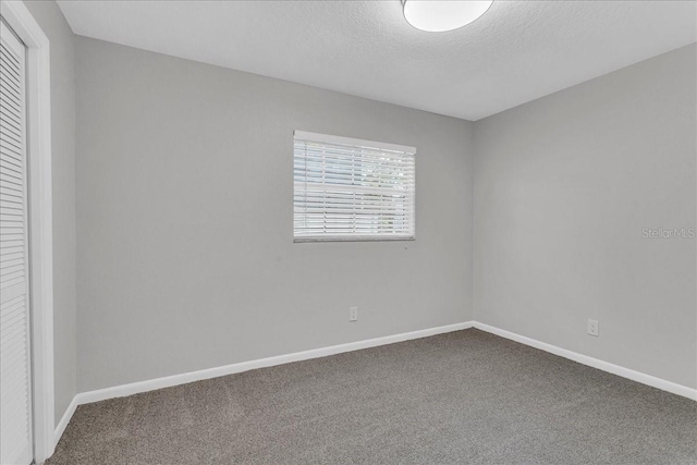 unfurnished room with a textured ceiling and carpet